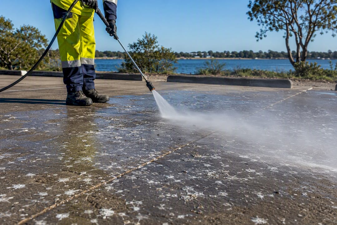 Operator pressure washing bird droppings on parking lot