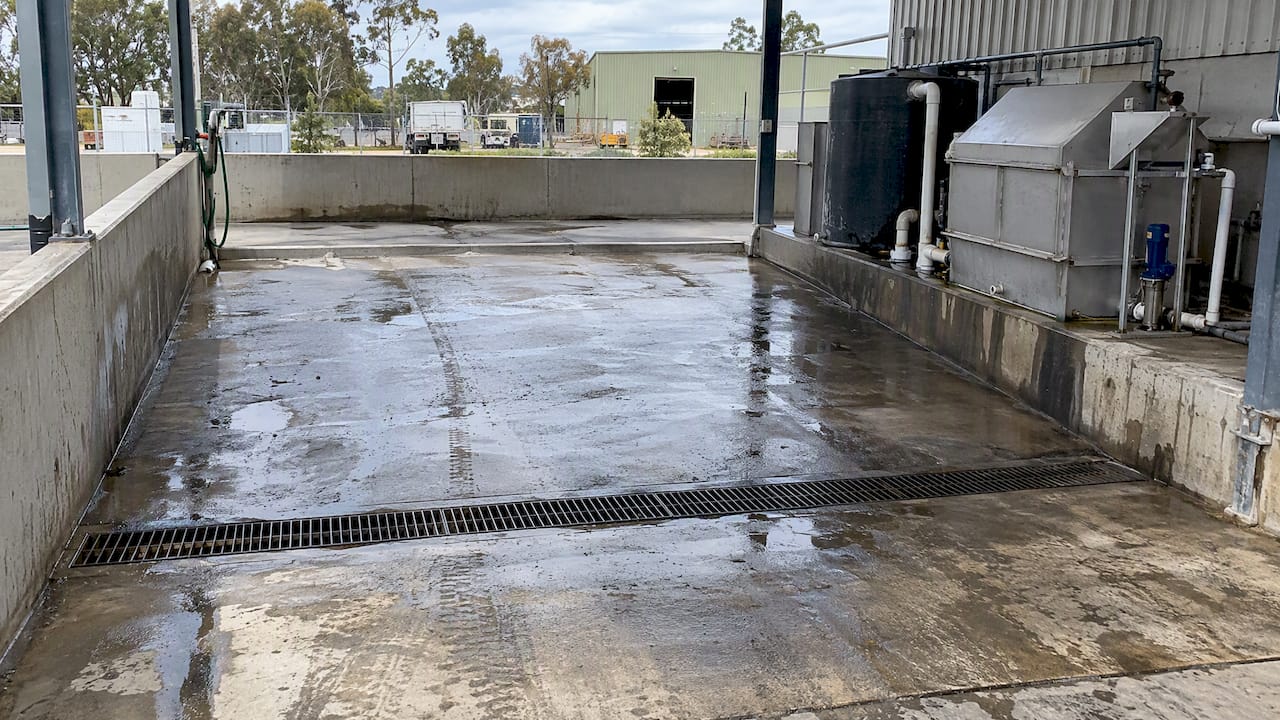 Commercial wash bay with drainage and treatment equipment
