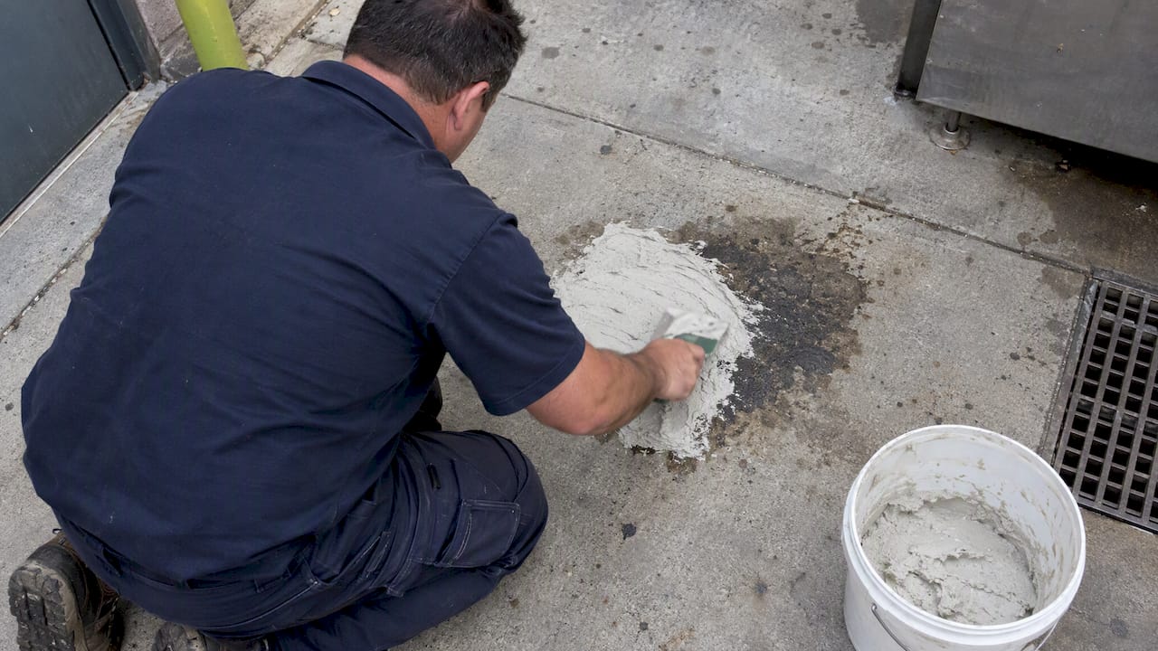 Worker treating an old concrete oil stain